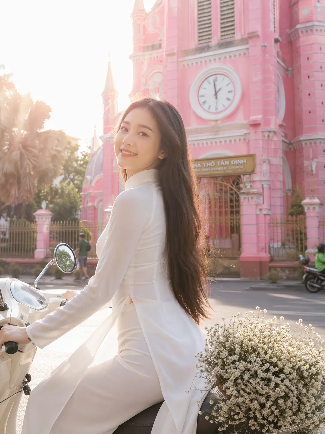 身穿白色奥黛的女导游在胡志明粉红教堂前骑乘摩托车
